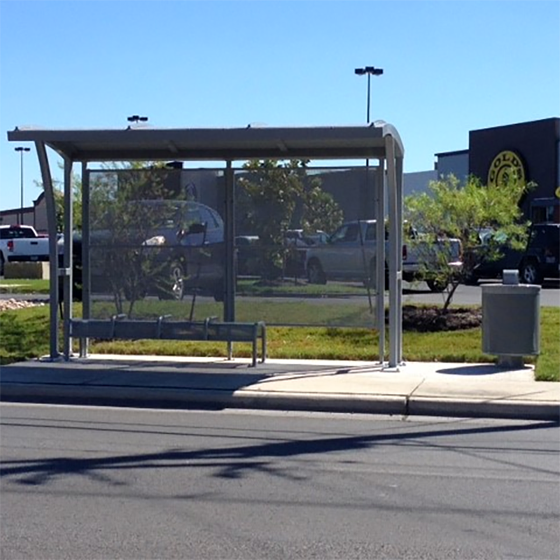 A front view of a bus shelter with bench seating and a trash can near by
