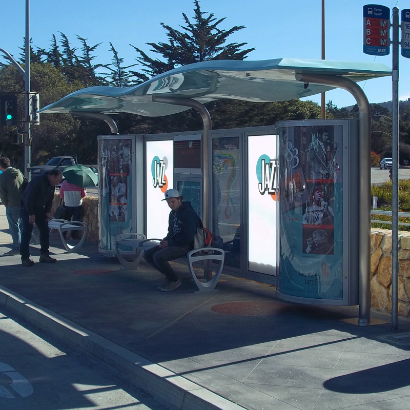 A custom Jazz themed bus shelter with two benches and rider info displayed in the middle as passengers sit and observe the shelter
