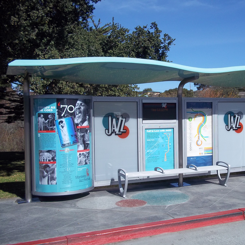 A left side view of a custom bus shelter with Jazz history decorated on the end of the shelter, bench seating in the middle and rider info behind the bench