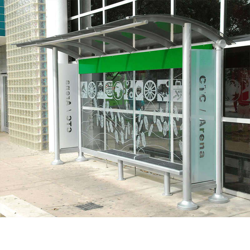 A right side view of a bus shelter with a custom back wall design and sign panels reading CTC/Arena and bench seating inside the shelter.