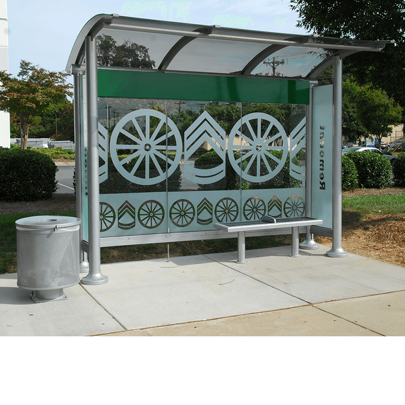 A bus shelter with a trash receptacle on the left side and a designed back wall to the shelter and bench seating inside the shelter.