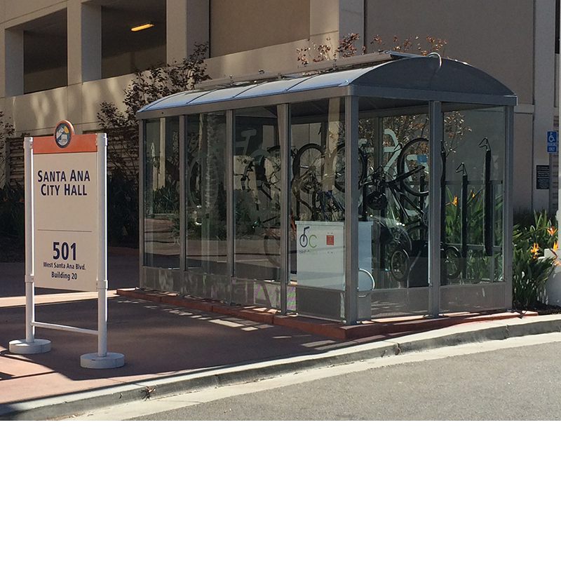 A fully enclosed bike shelter with hanging locked bikes outside the Santa Ana city hall.