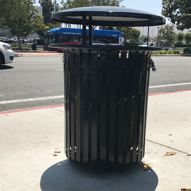A trash receptacle with an opening around the sides but covered on top.