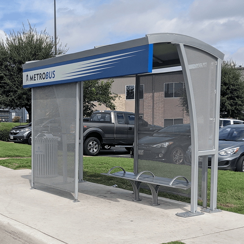A metro bus shelter with bench seating inside the shelter and a trash receptacle on the outside left.