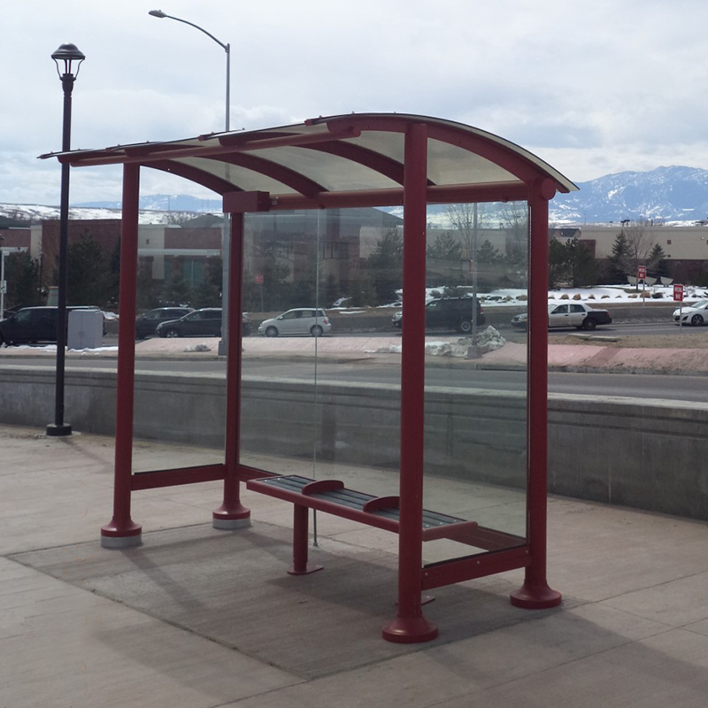 A bus shelter seen from the front right with bench seating and glass side paneling.