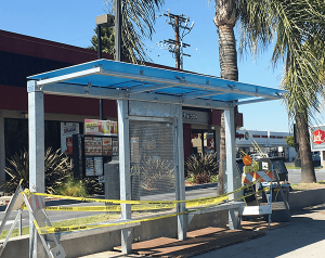 A bus shelter with caution tape all around as it is under construction.