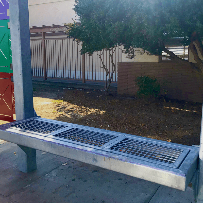 Metal bench on the custom bus shelter, grated seats and open back to the bench