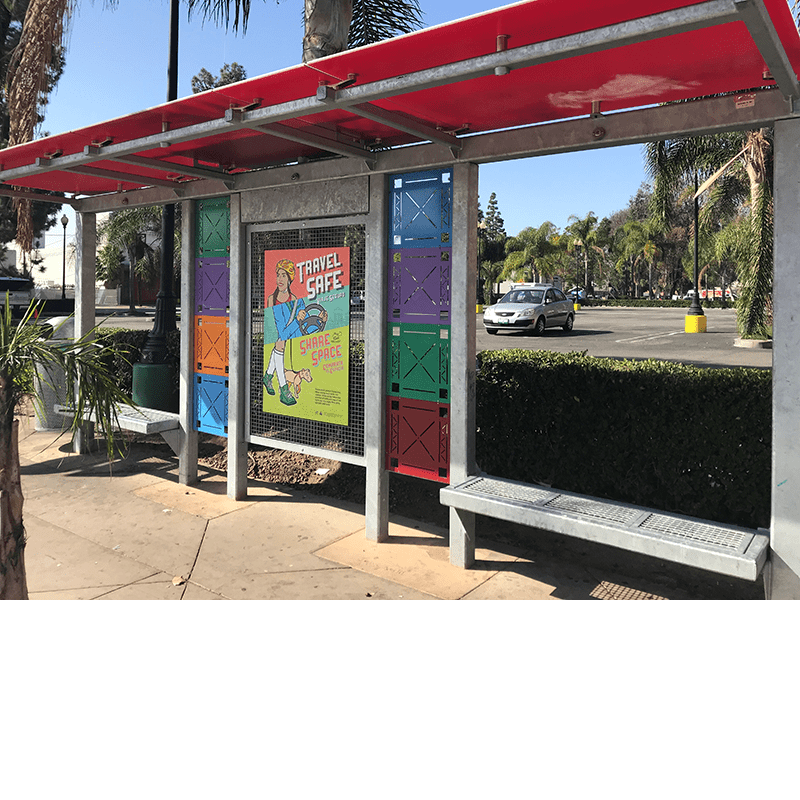 Full left side view of the custom design bus shelter with colored square elements, advertising displays and open back benches