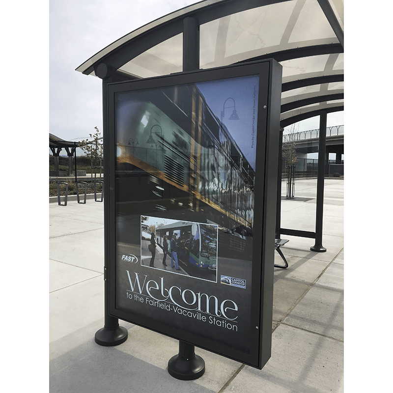 A siga sunset shelter's advertising display on the left side panel is seen from the outside of the shelter with an advertisement for the station.