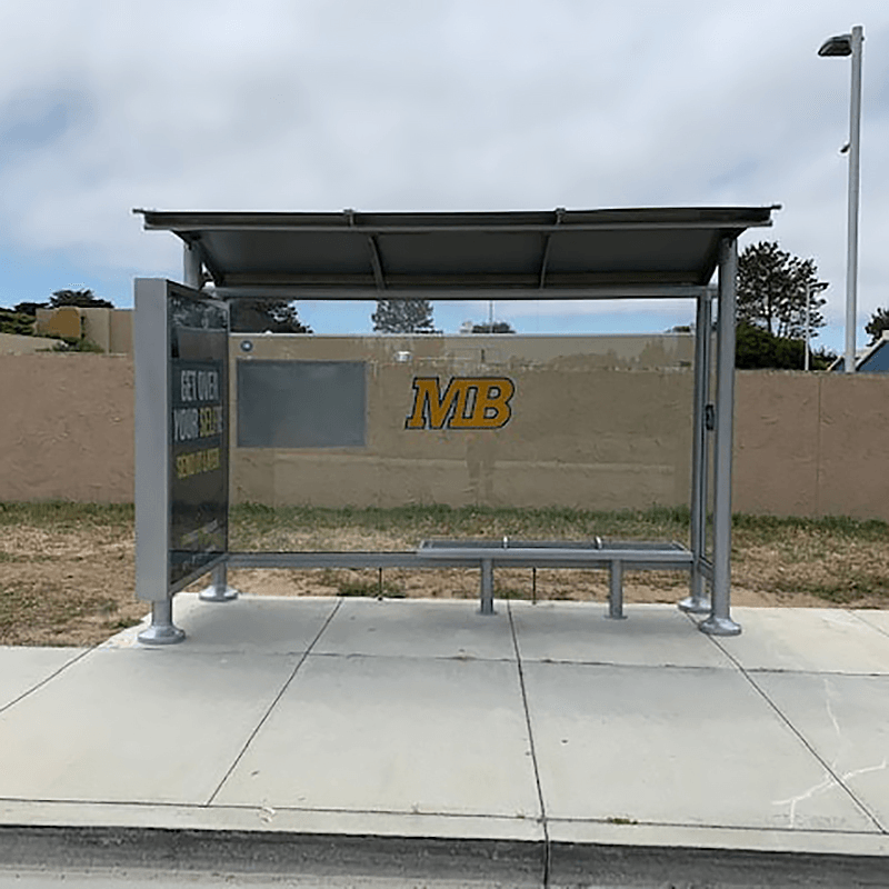A siga sunset bus shelter with glass siding, a rider information display on the back panel, a custom MB logo on the back and bench seating for three.