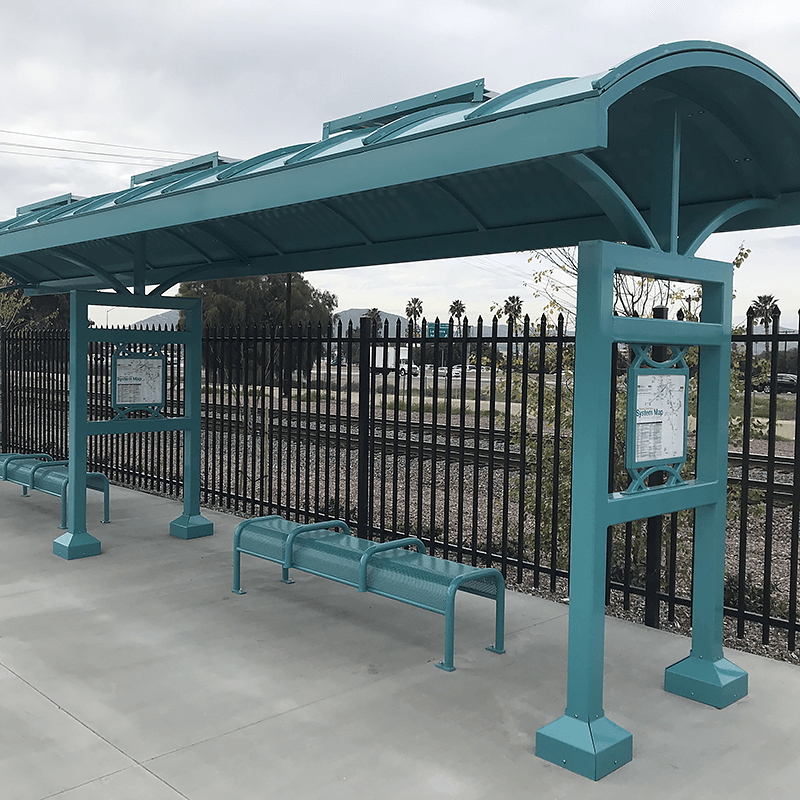 A signa custom bus shelter seen from the front right with two shelters side by side with bench seating under both and rider information on the posts.