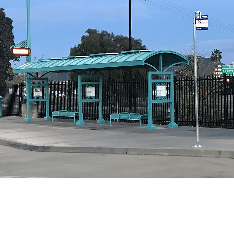 A signa custom bus shelter is seen with two shelters side by side with bench seating under each and rider information on all three posts.