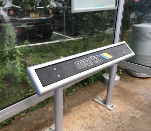 close-up photo of lean rail in bus shelter with MARTA logo imprinted Marta standing/leaning bench under a bus shelter