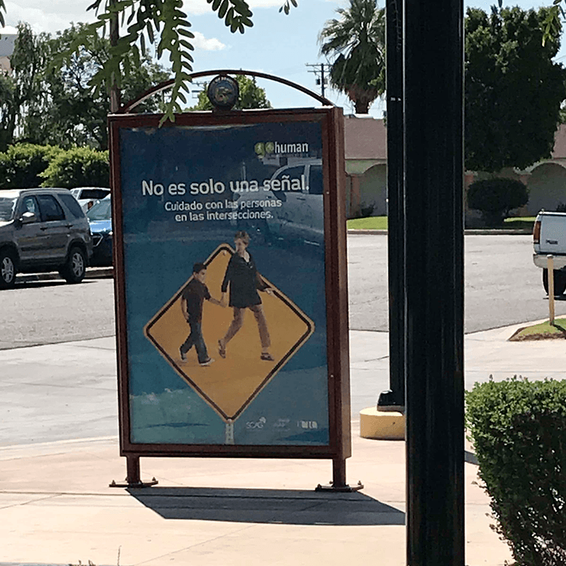 A double sided advertisement/rider information display is seen on a sidewalk.