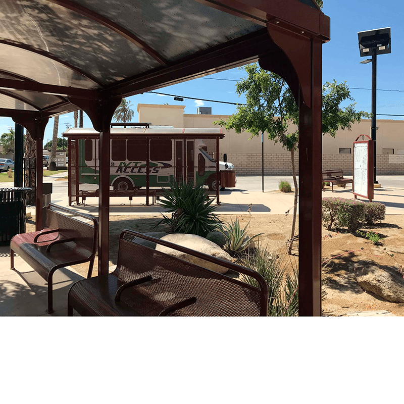 Multiple bus shelters are seen scattered throughout a landscaped area with benches under the shelters and trash receptacles placed on the outside.