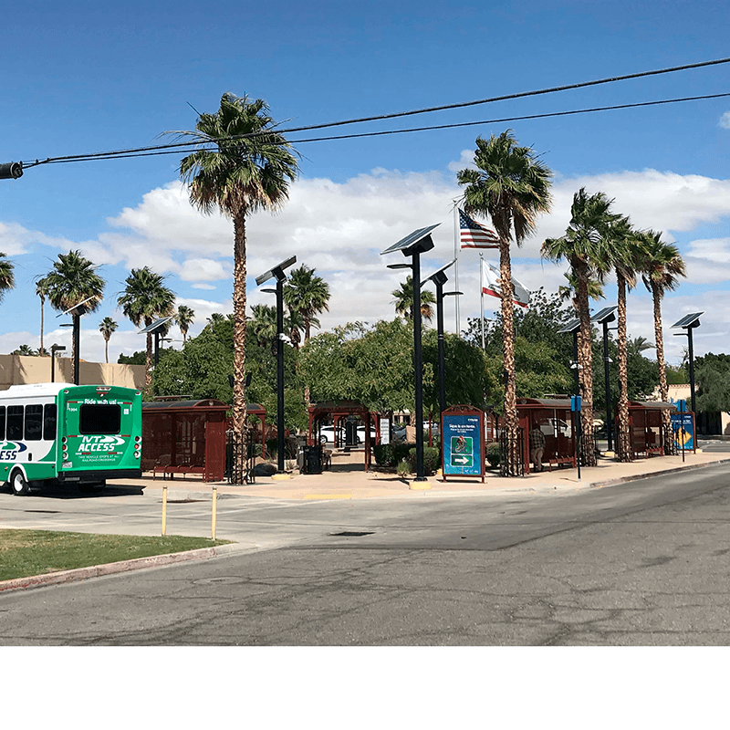 Multiple bus shelters in a block with information/advertising displays, solar posts and flags with a bus at the curb.