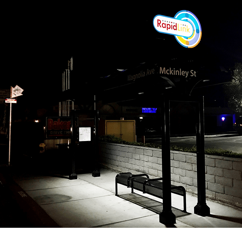 Evening view of a RapidLink bus shelter with lighting, bus information display and bench seating