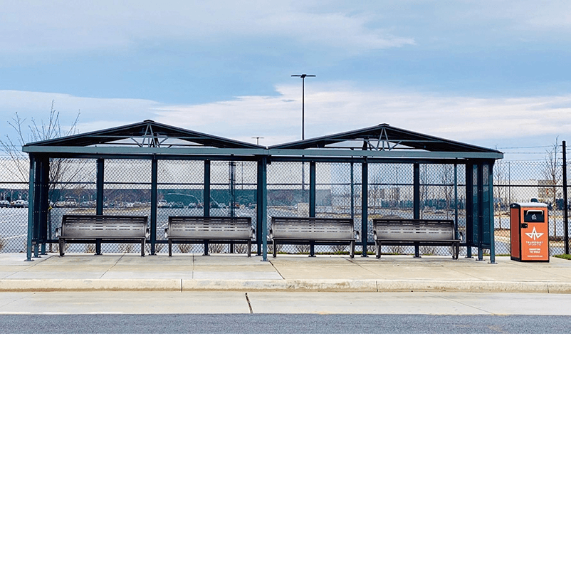 Two bus shelters with a pitched roof, two benches for seating inside each of the shelters and a trash receptacle on the right side.