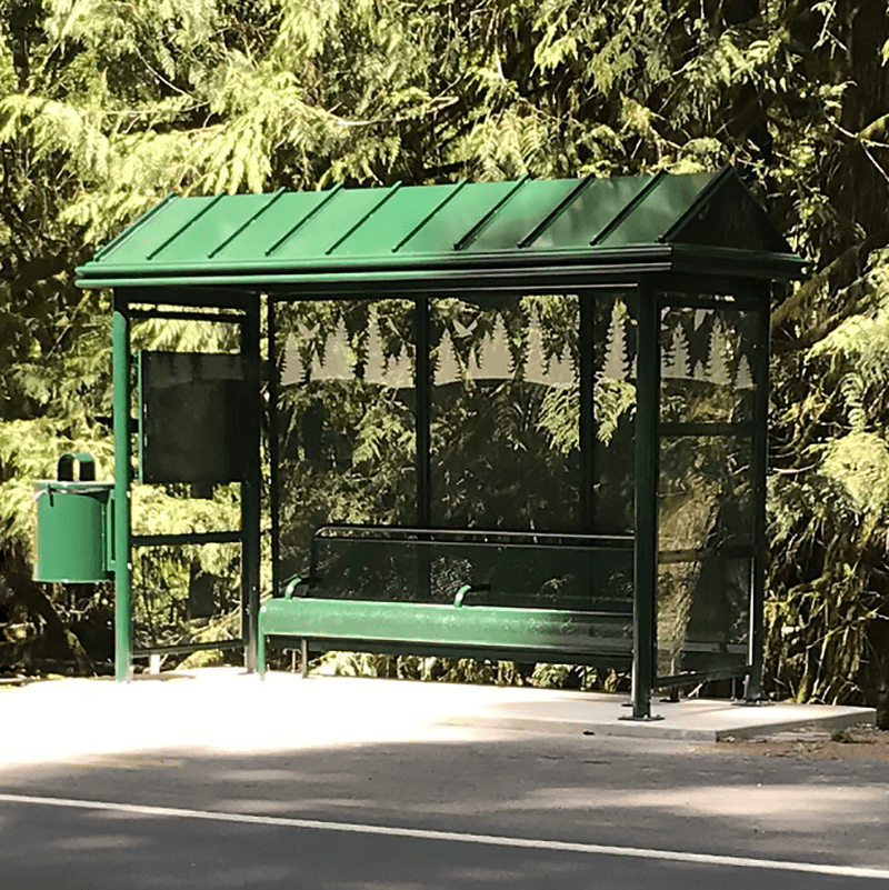 A bus shelter seen from the front right with bench seating inside, rider information display on the inside left panel and a trash receptacle attached to the outside left.