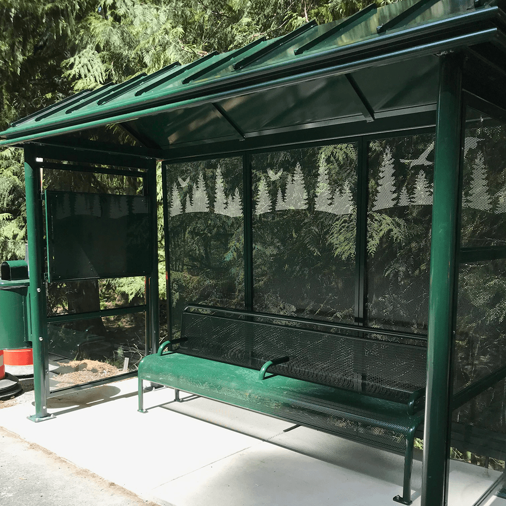 A bus shelter with bench seating, a rider information display on the left side panel and a trash receptacle attached on the left outside.