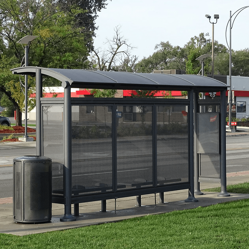 The back of a signa bus shelter with a trash receptacle on the outside, bench seating inside and a right side rider information display.