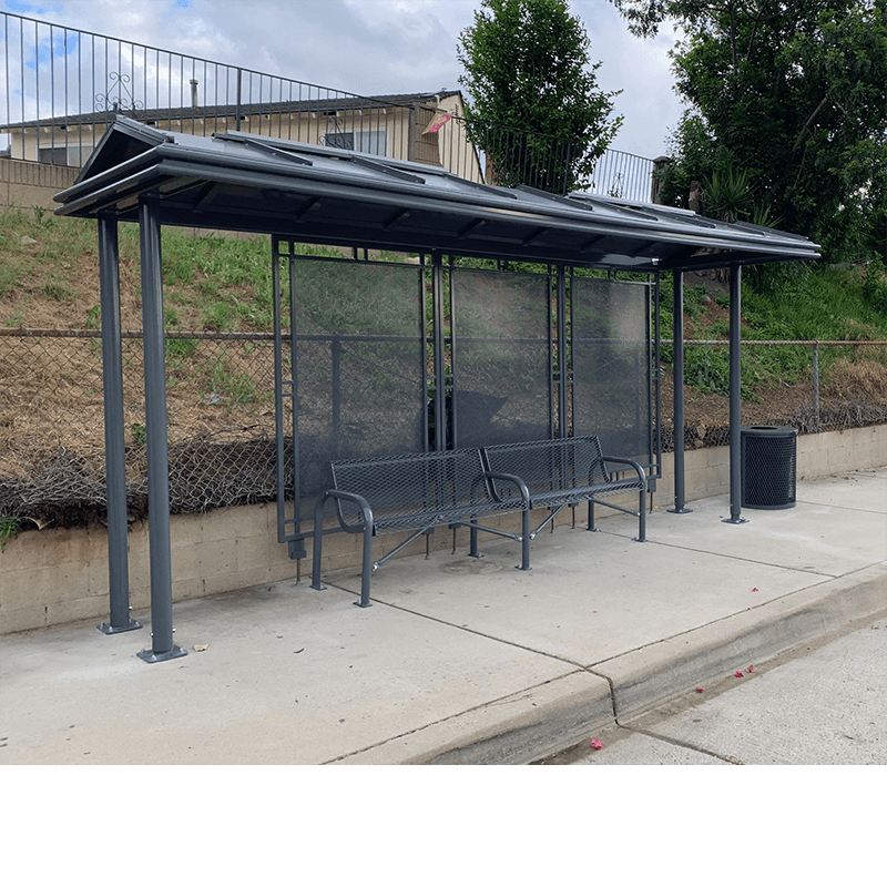 A bus shelter with two benches and a trash receptacle on the outside right side.