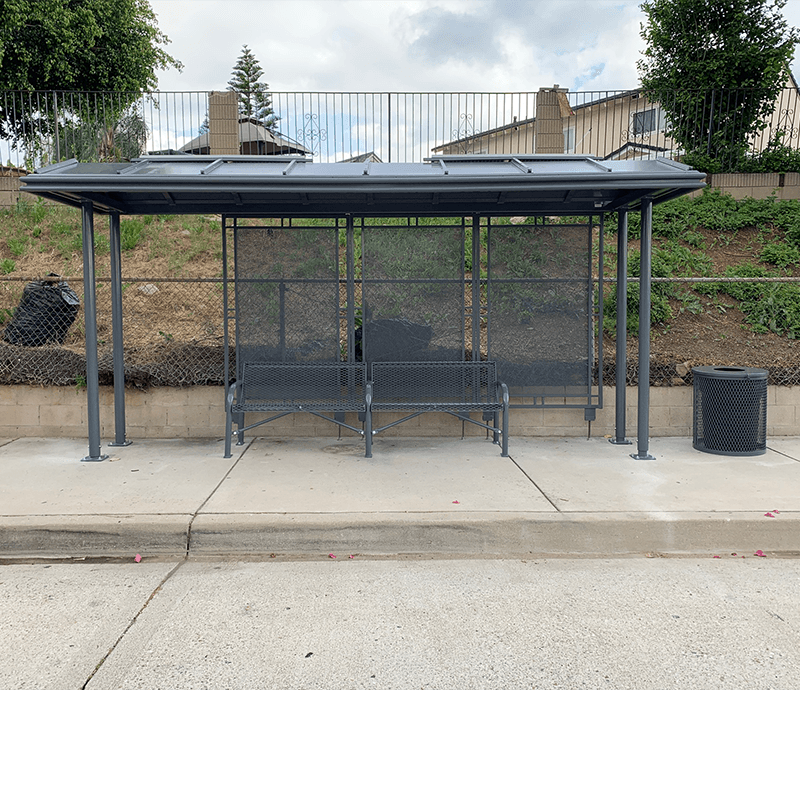 A bus shelter with two benches and a trash receptacle on the outside right side.