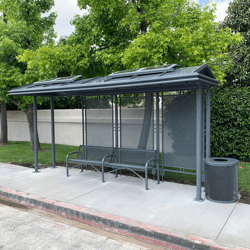 A bus shelter with two benches inside the shelter and a trash receptacle on the outside right.