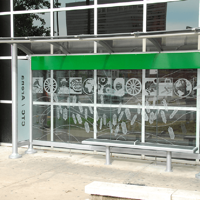 A bus shelter with bench seating inside a custom designed back wall with coffee cups, a wheel and other images.