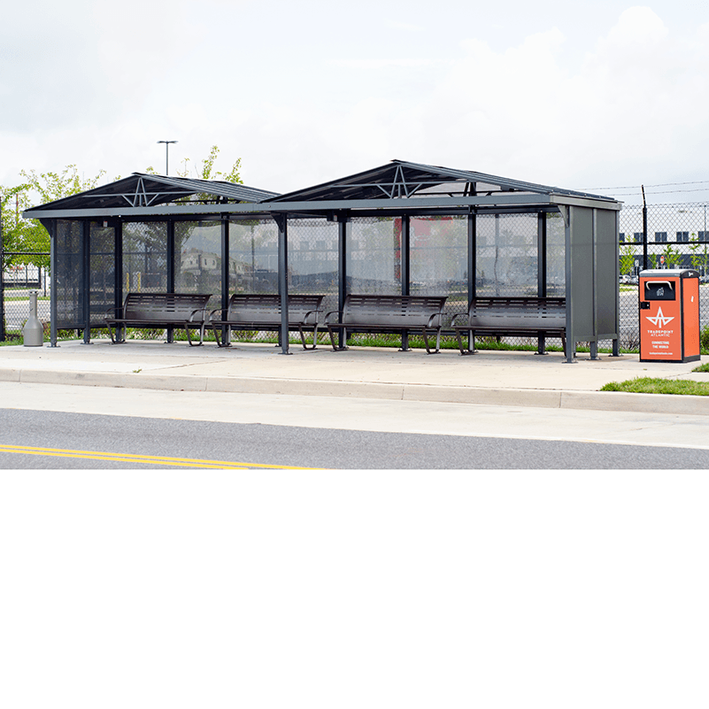 A stood back view of bus shelter with a peaked roof, four benches and a trash receptacle on the outside right.