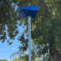 The top of a bus stop post is seen with a blue box light.