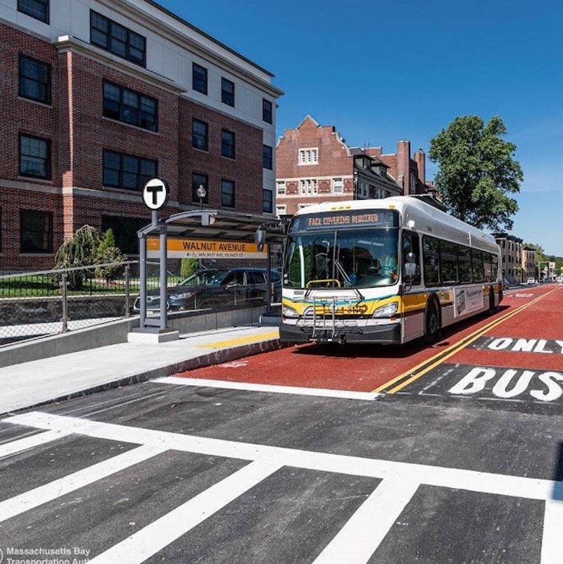 A bus in Boston pulls up to a bus shelter with Walnut Avenue displayed across the back