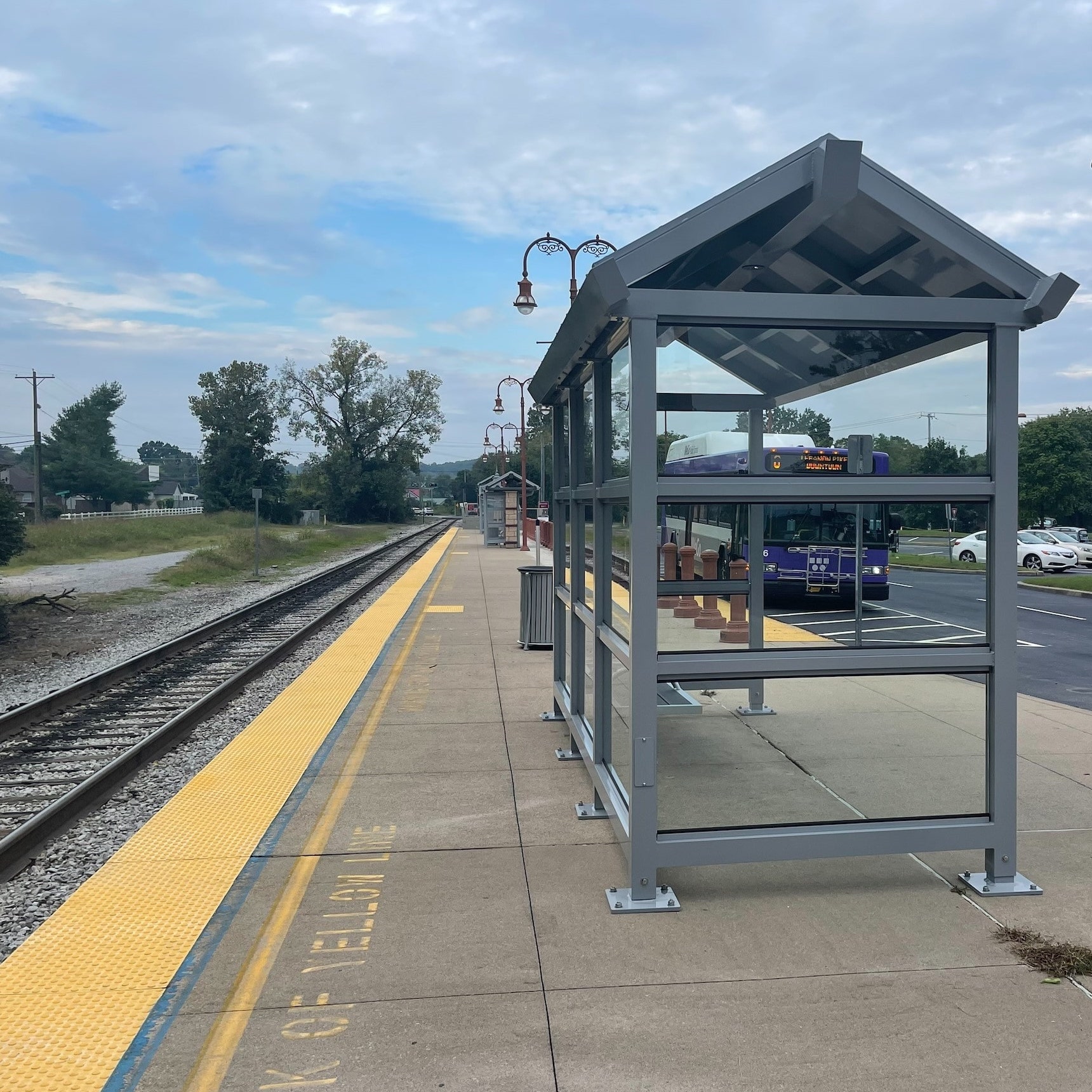The back left of a bus shelter is seen alongside a set of tracks.