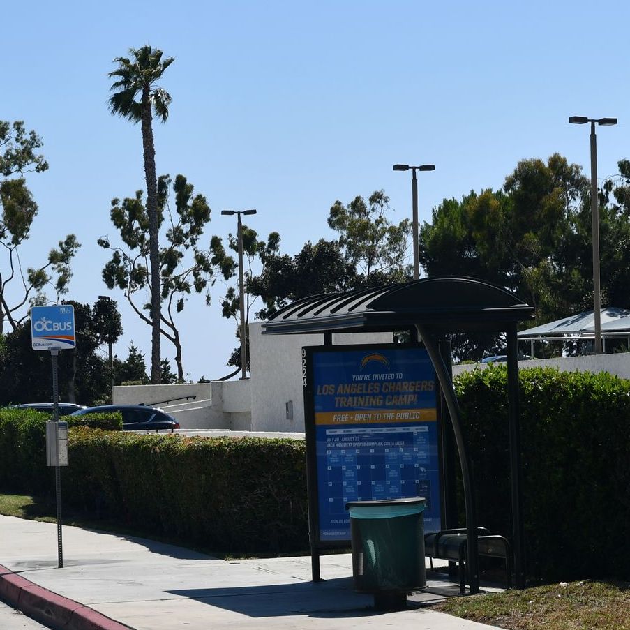 Left side view of a 13' Sierra Dome Roof Advertising Transit Shelter with radius upstream support post, bench and trash receptacle