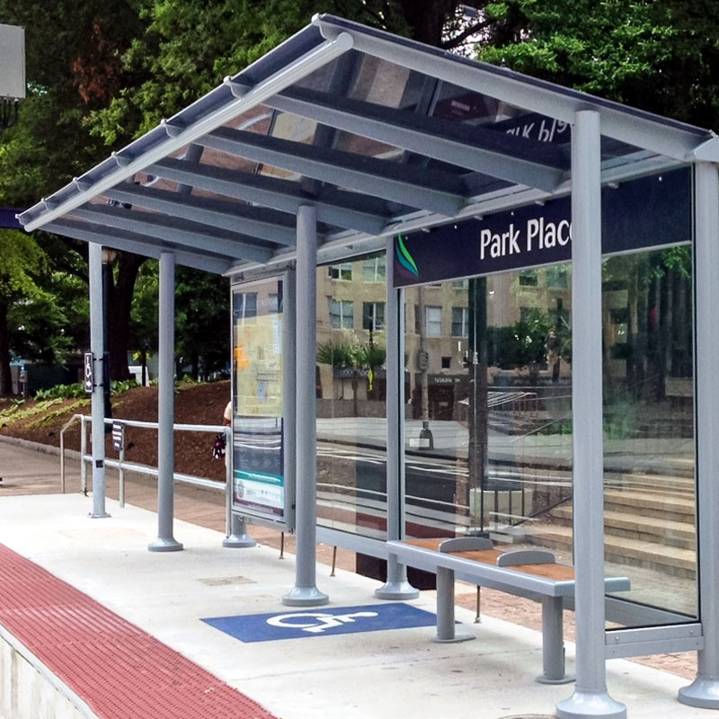 A street car transit shelter seen from the left side with bench seating, rider information display and a dedicated handicap spot for wheel chairs