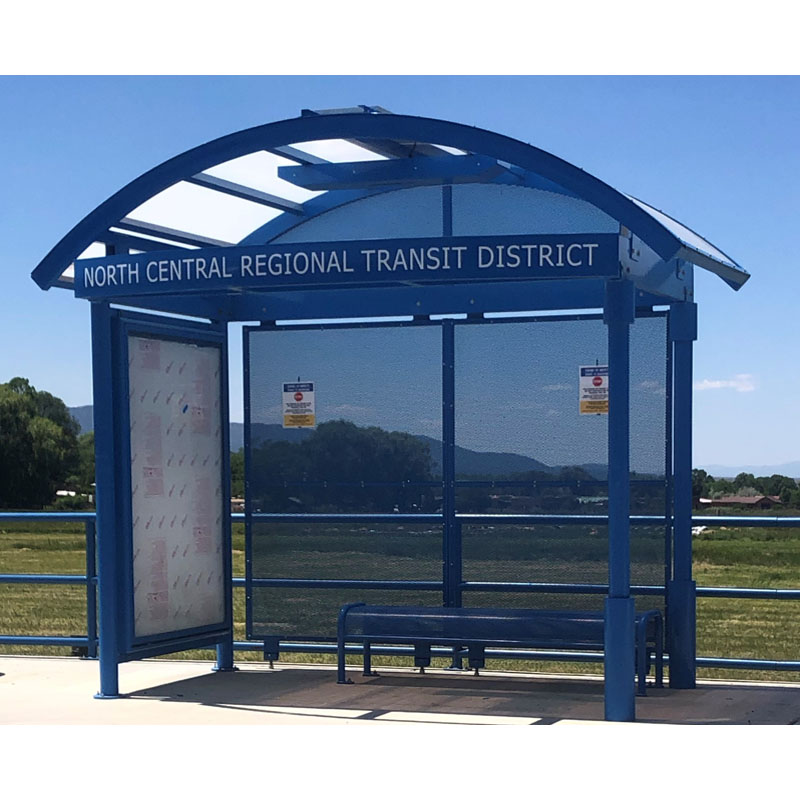 A bus shelter is seen from the front for North Central Regional Transit District with a double sided advertising display on the left panel and bench seating.