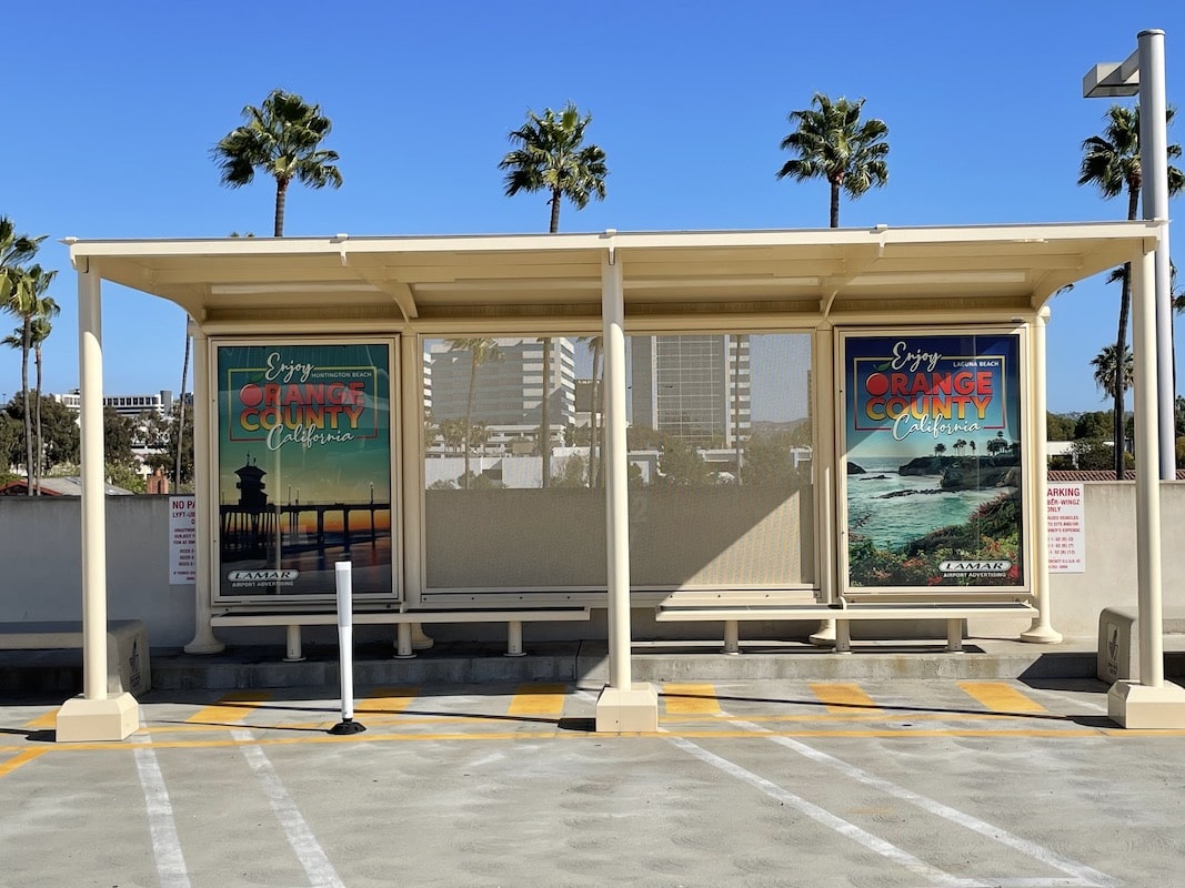 A bus shelter is seen from the front with two advertising displays on the two back side panels and two benches.