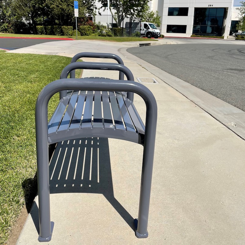 A two seater bench is seen from the side with no back and three handles.