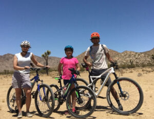 Three people standing next to bikes in the desert.