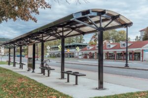 A bus shelter is seen alongside Lake George with an information kiosk in the middle and bench seating on their side.