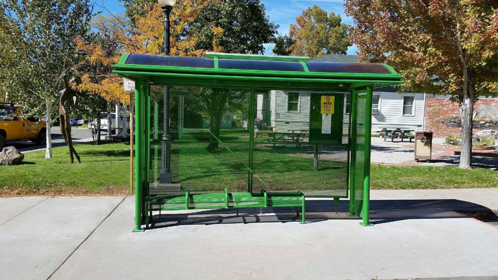 A sierra series bus shelter is seen from the front with a bench seating for four and a rider information display on the back right panel.