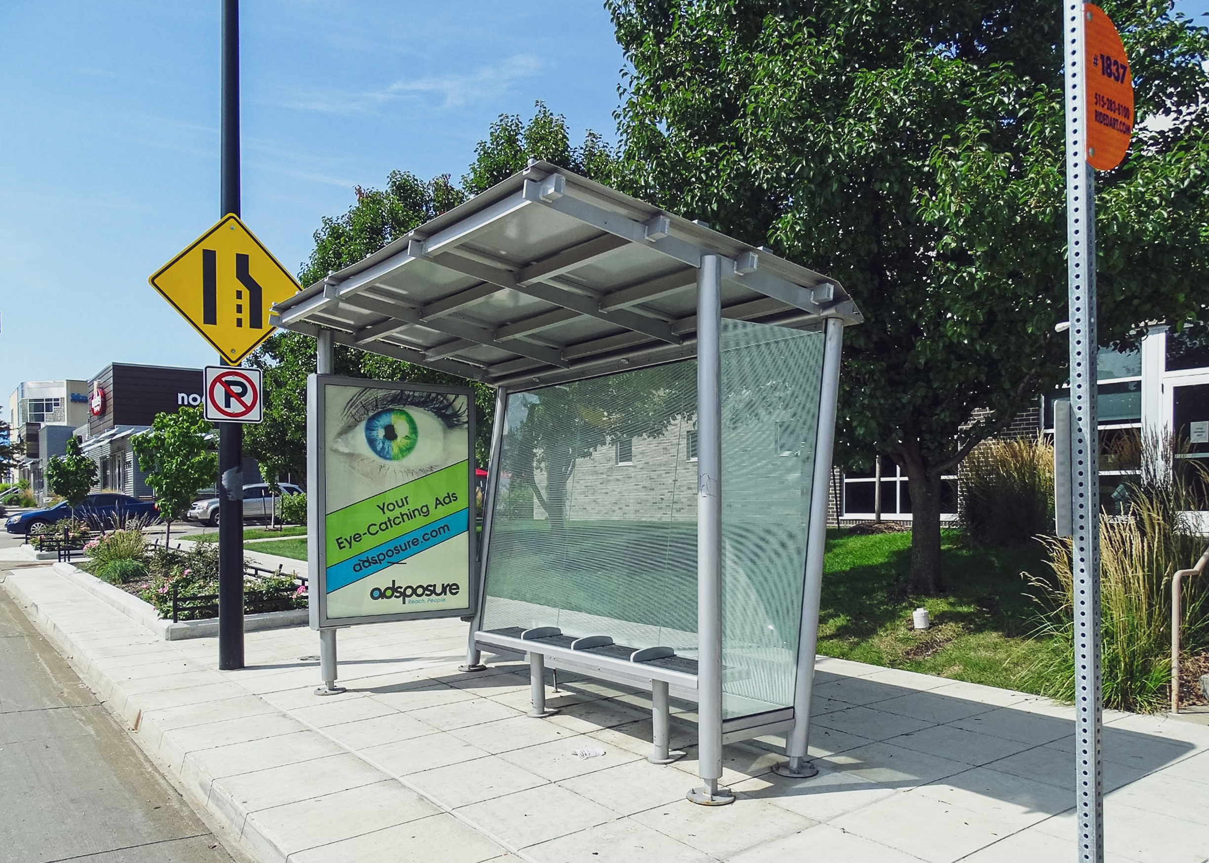 A signature orion bus shelter with an advertising display on the left side and bench seating for four.