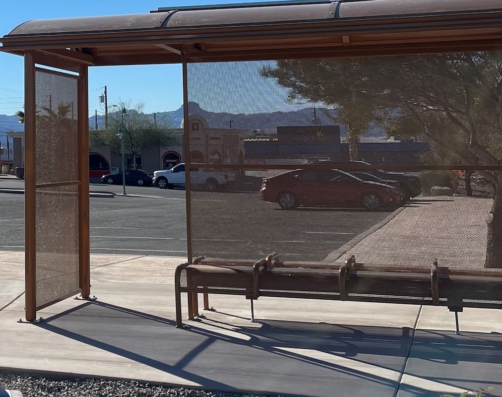 Front view of a brown bus shelter with bench seating and a dome roof