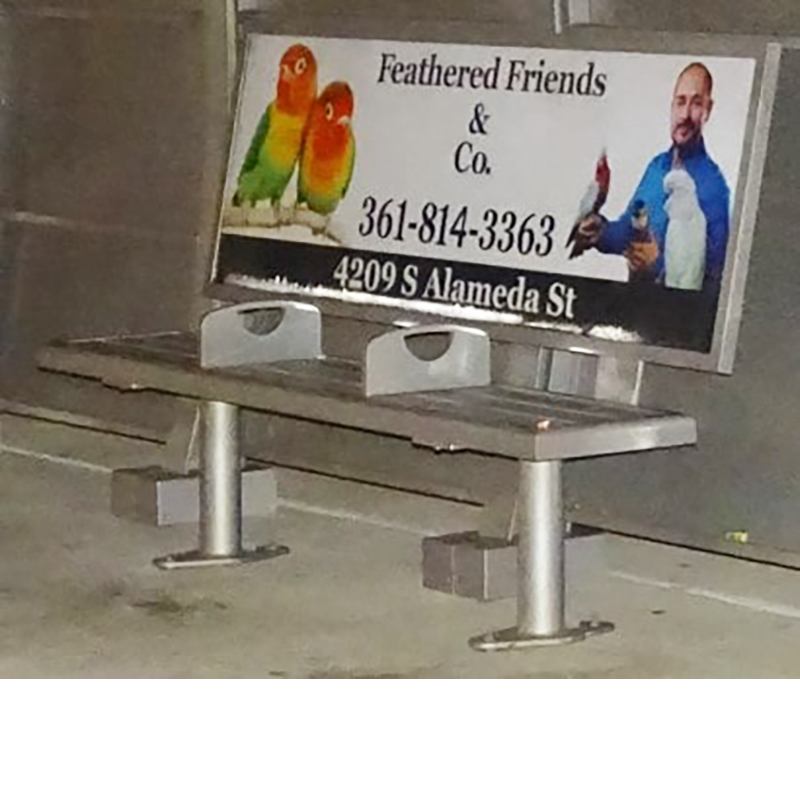 A bench inside a bus shelter with an advertising display on the back rest.