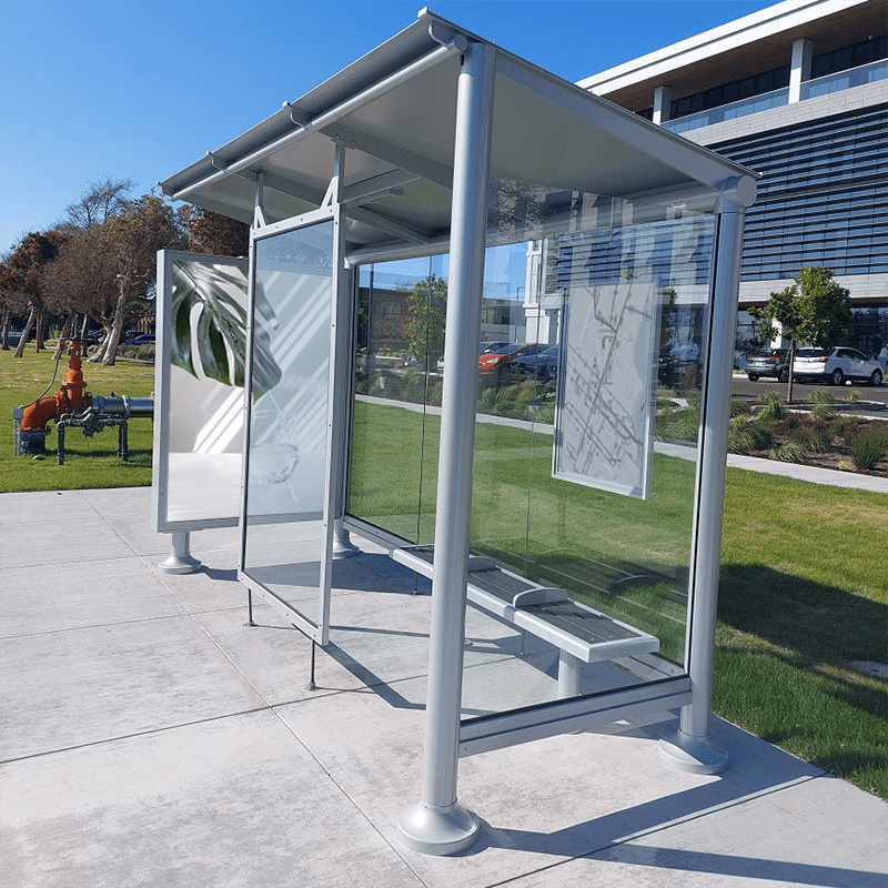 A siga empire bus shelter with glass siding, bench seating, rider information display and an advesting display on the left side panel.