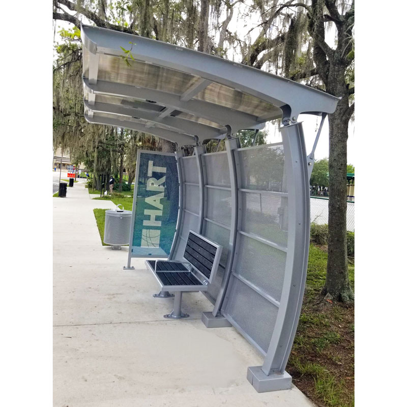 A signa crescent bus shelter for HART with an arched roof and back panel structure, bench seating and a trash receptacle on the outside left.
