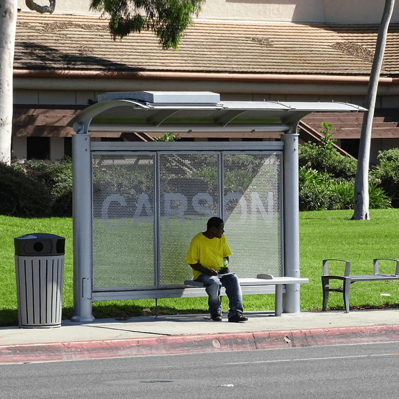 Man in yellow shirts sits on bus shelter bench in a signa custom bus shelter