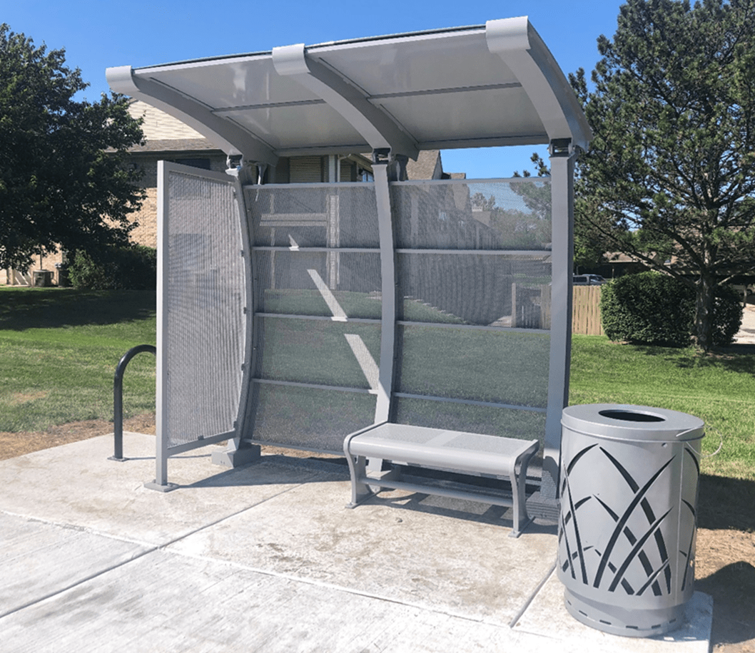 Small bus shelter with a bench and trash receptacle with a greenery design on the outside