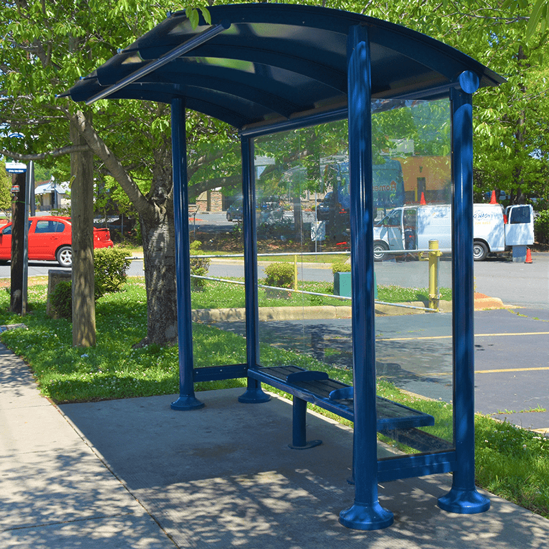 Tolar's Signa Sunset bus shelter in a deep blue with seating, plenty of shade and a glass siding