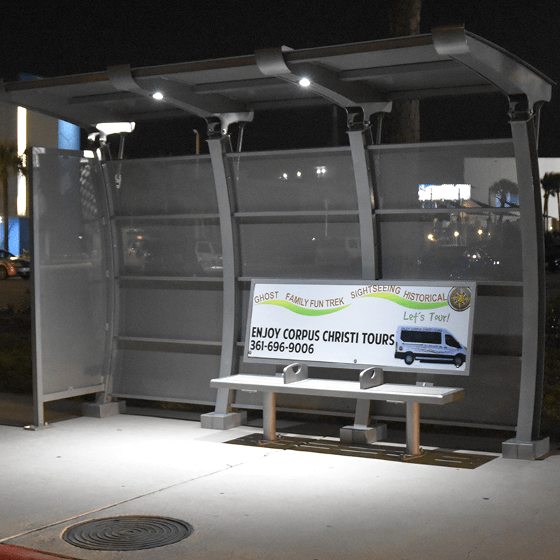 Evening lit bus shelter that includes well lit advertising on the shelter's bench